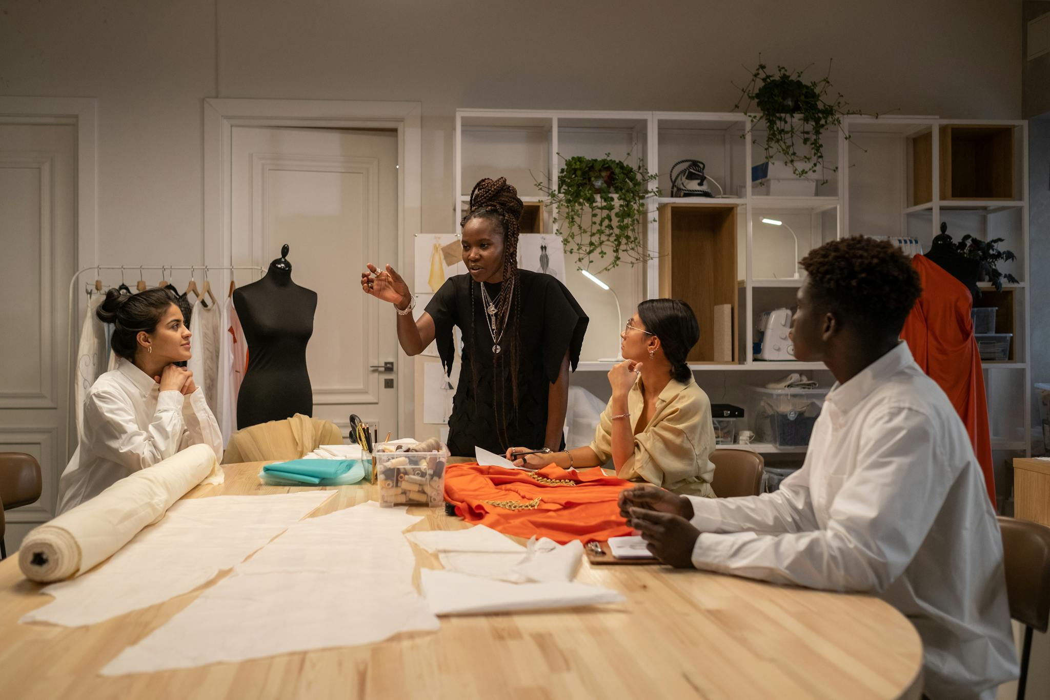 A diverse fashion design team collaborates in an atelier, focusing on creative solutions.